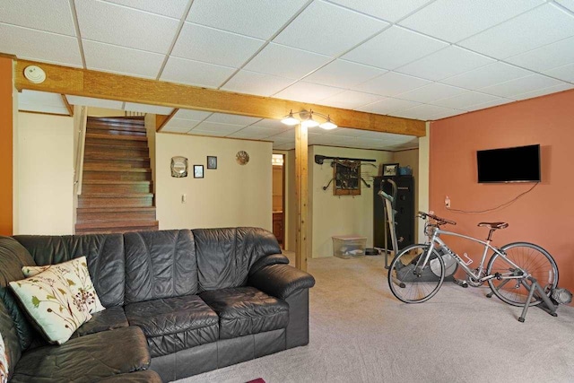 living room with a drop ceiling, carpet flooring, and stairway