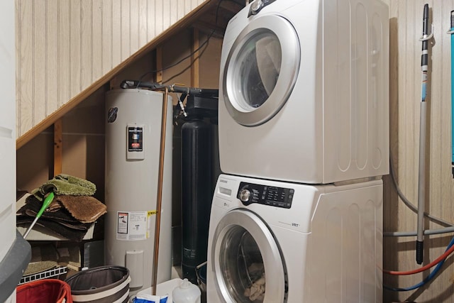 laundry area featuring water heater, stacked washer / dryer, and laundry area