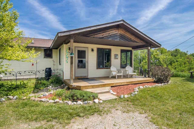 rear view of property with a yard, a deck, and fence