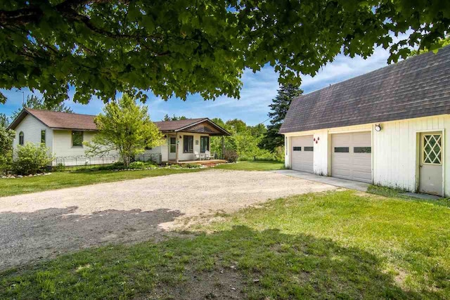 view of front facade with a front lawn, roof with shingles, an outdoor structure, and driveway