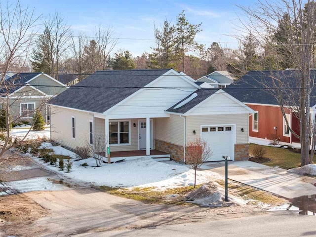 view of front of home featuring a garage, stone siding, driveway, and a shingled roof