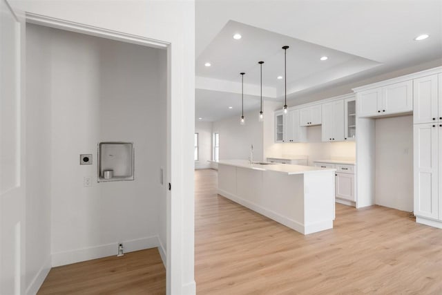 kitchen featuring recessed lighting, white cabinets, light wood-type flooring, and a tray ceiling