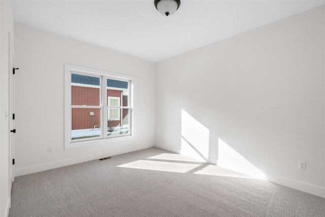 carpeted spare room featuring visible vents and baseboards