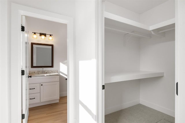 bathroom featuring vanity, a spacious closet, wood finished floors, and baseboards