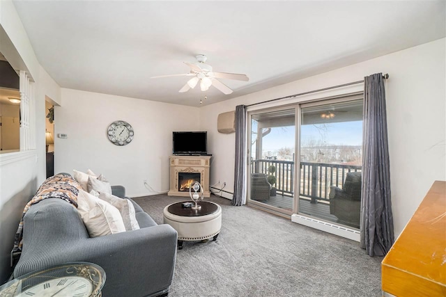 living area with a lit fireplace, a baseboard heating unit, a ceiling fan, and carpet floors