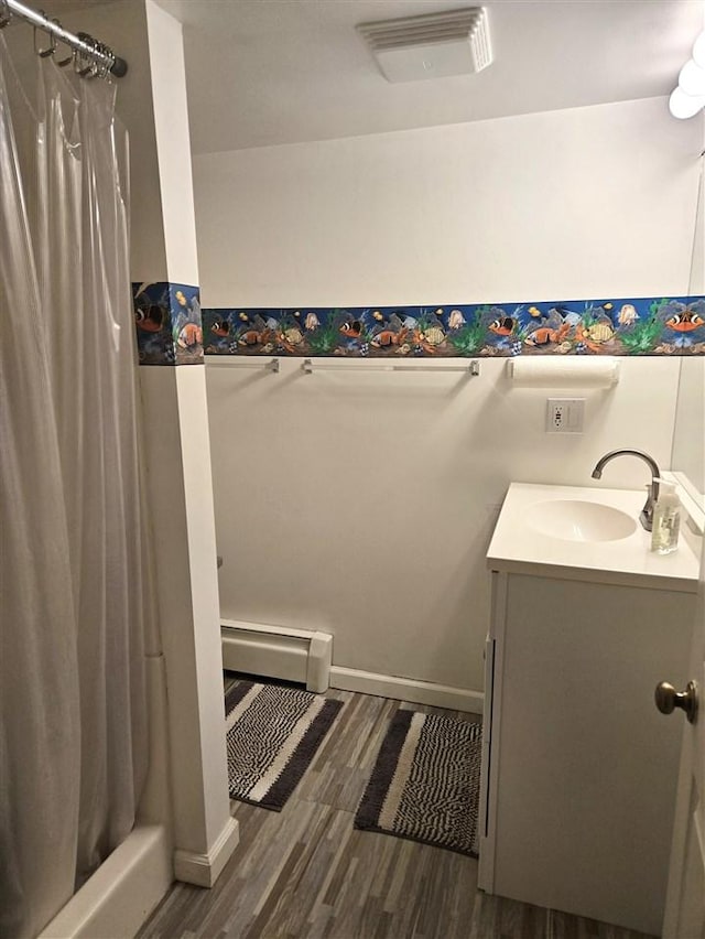 bathroom with visible vents, a shower with shower curtain, wood finished floors, vanity, and a baseboard radiator