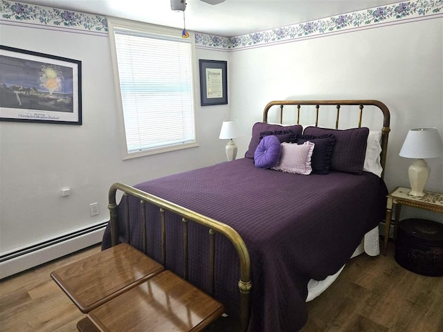 bedroom featuring a baseboard heating unit, a ceiling fan, and wood finished floors