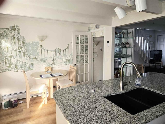 kitchen featuring stone countertops, light wood finished floors, and a sink