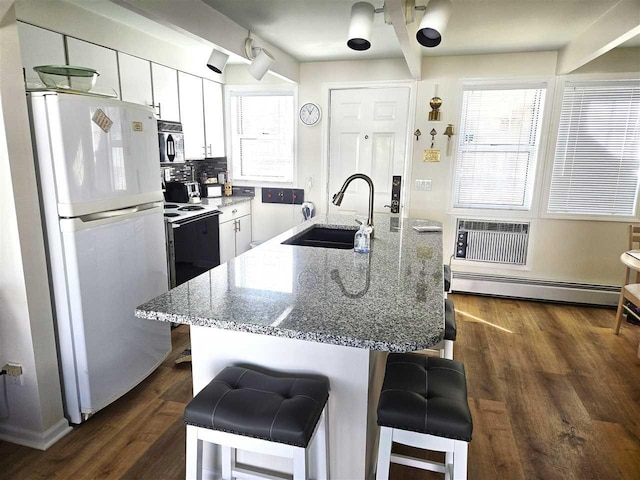 kitchen with a breakfast bar, a wall mounted AC, a sink, freestanding refrigerator, and black microwave