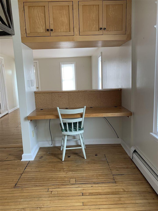 interior space with baseboard heating, light wood-style flooring, breakfast area, and baseboards