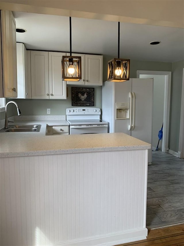 kitchen with decorative light fixtures, a peninsula, wood finished floors, white appliances, and a sink