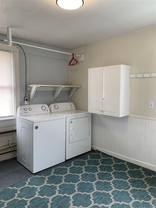 laundry room featuring washer and dryer, cabinet space, and wainscoting