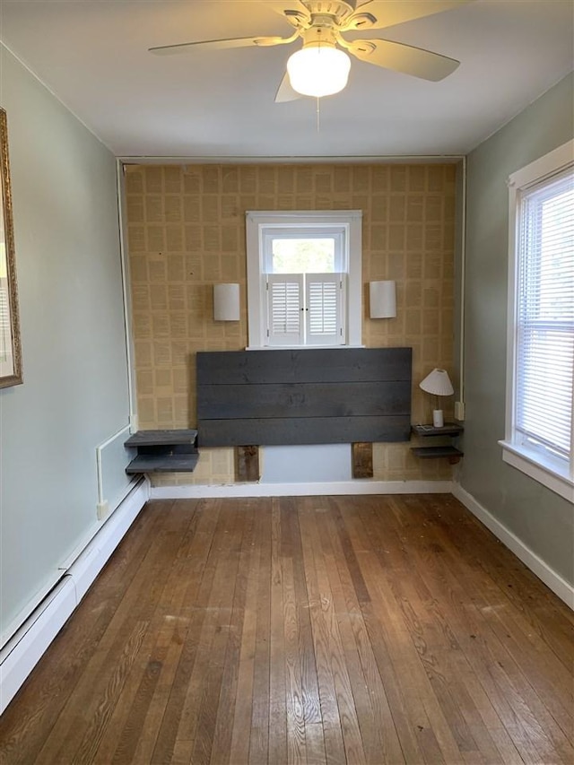 unfurnished living room featuring a baseboard radiator, baseboards, hardwood / wood-style floors, and a ceiling fan