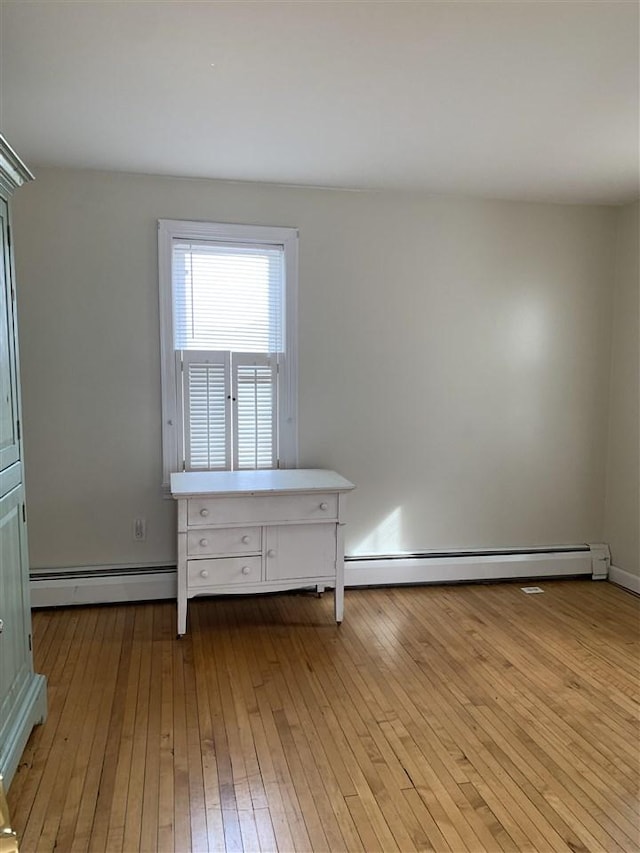 unfurnished room with a baseboard radiator and hardwood / wood-style flooring