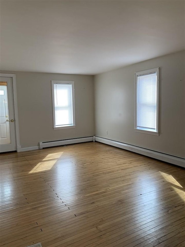 empty room with baseboard heating, baseboards, and hardwood / wood-style flooring