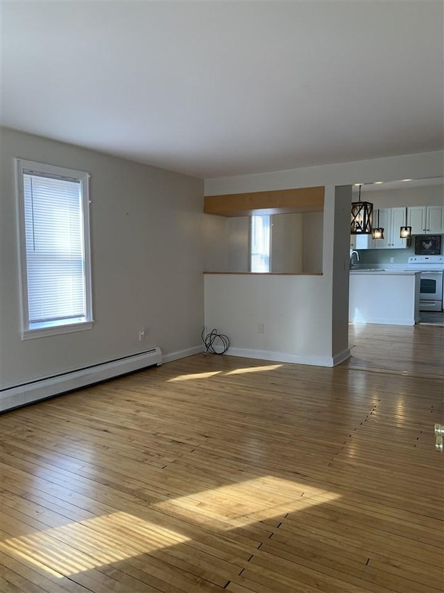 unfurnished living room featuring a sink, a baseboard radiator, baseboards, and dark wood finished floors