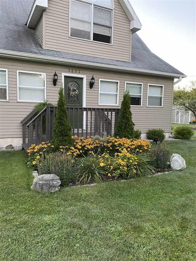 view of front facade with a front yard and roof with shingles