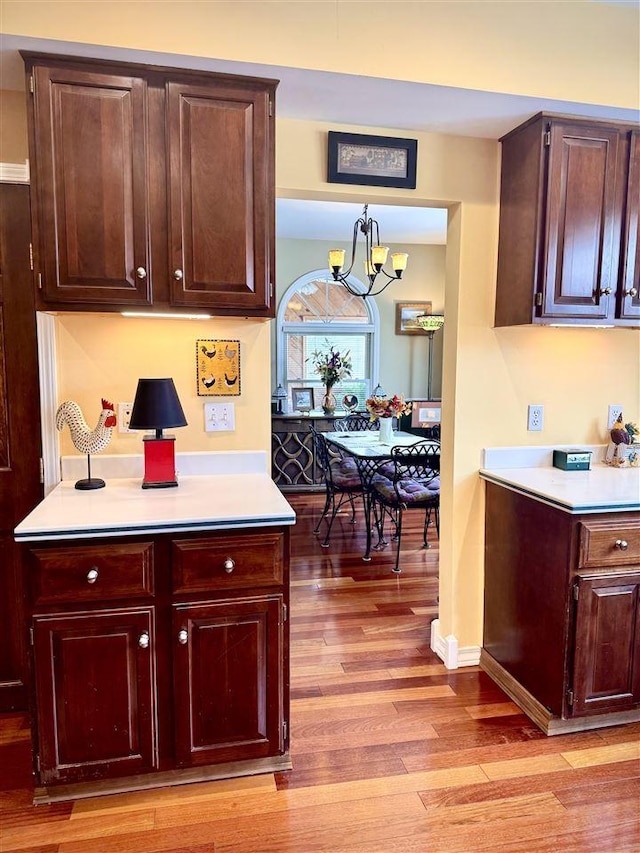 kitchen featuring baseboards, light wood-type flooring, light countertops, and an inviting chandelier