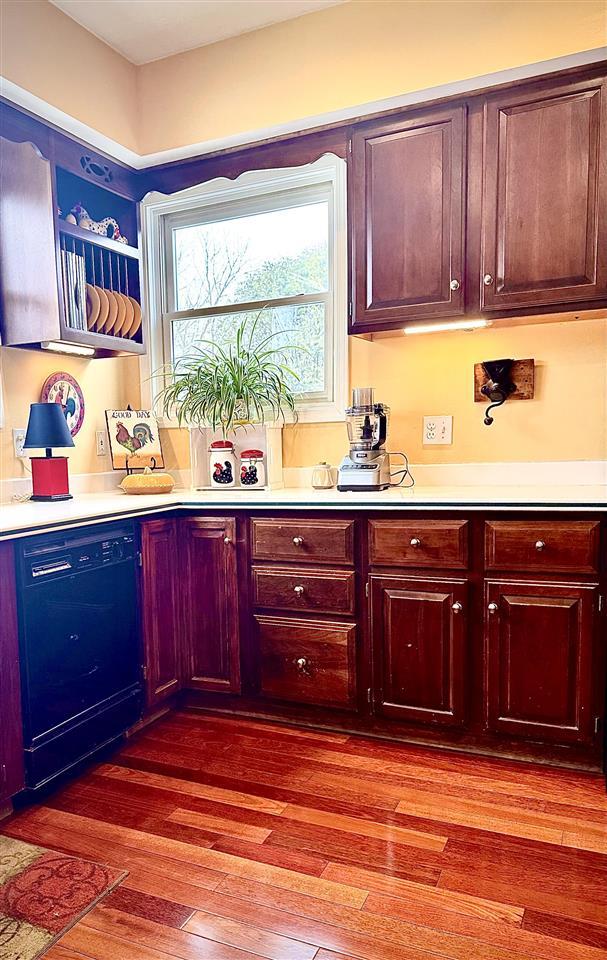 kitchen featuring dishwasher, light countertops, and wood finished floors