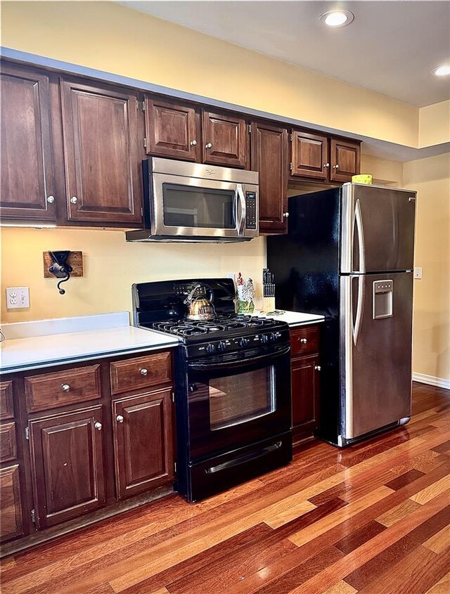 kitchen featuring stainless steel appliances, light wood-style floors, dark brown cabinetry, and light countertops