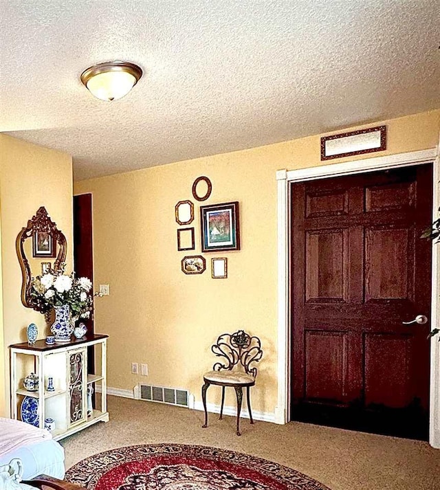 carpeted bedroom featuring visible vents, baseboards, and a textured ceiling