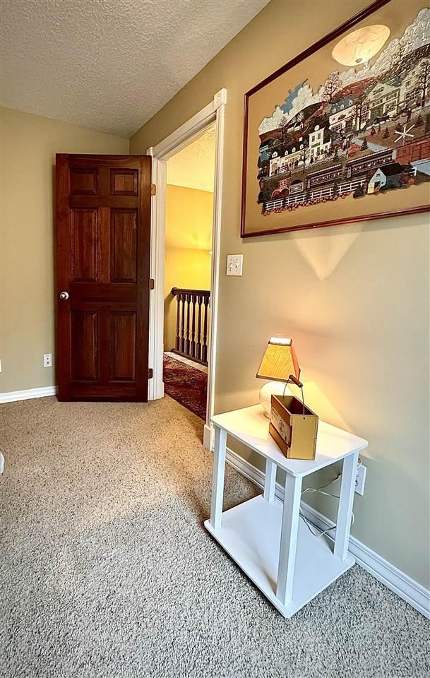 hallway featuring baseboards, a textured ceiling, and carpet flooring