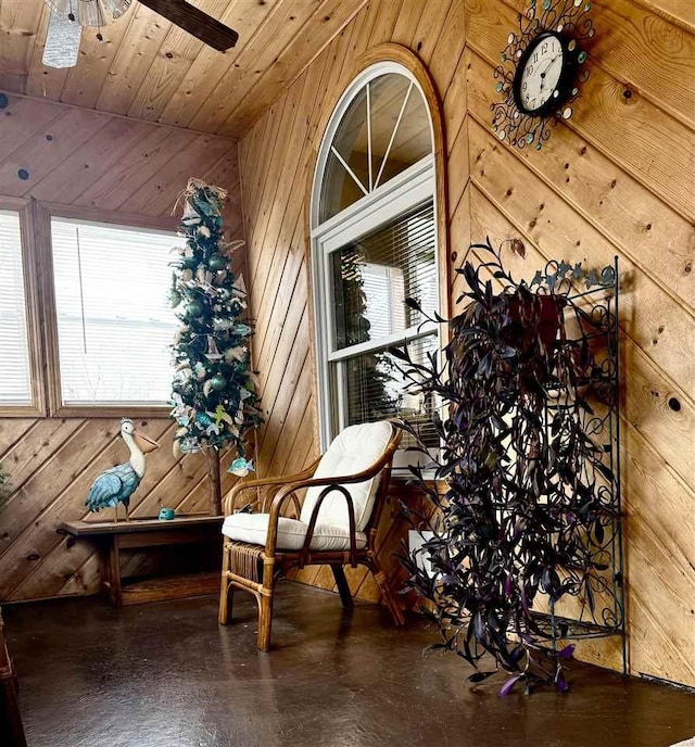 sitting room featuring wooden walls, wood ceiling, and ceiling fan