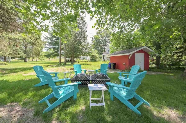 view of yard with a storage shed, a fire pit, and an outbuilding