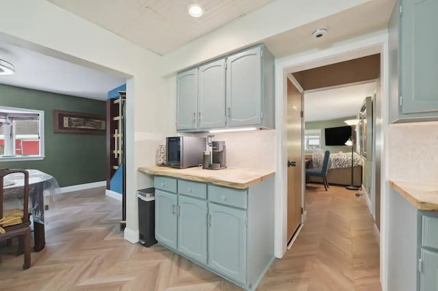 kitchen featuring baseboards, light countertops, and blue cabinetry