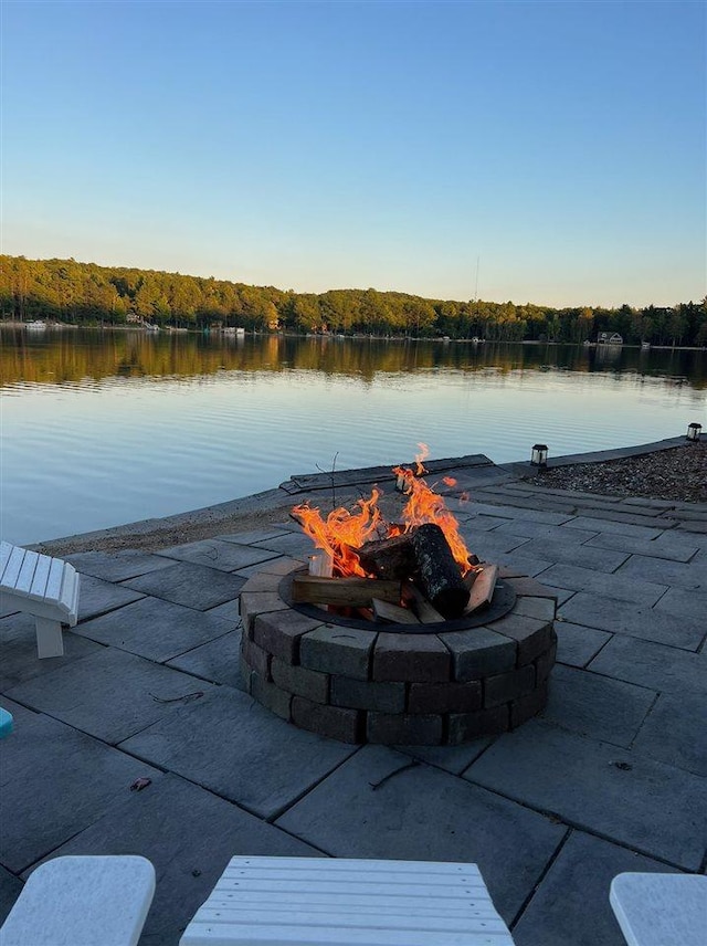 exterior space with a water view, a forest view, and an outdoor fire pit