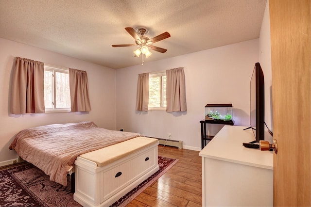 2382 Pleasant Valley Rd, Boyne City, MI 49712 - bedroom with baseboards, a baseboard radiator, a ceiling fan, light wood-type flooring, and a textured ceiling