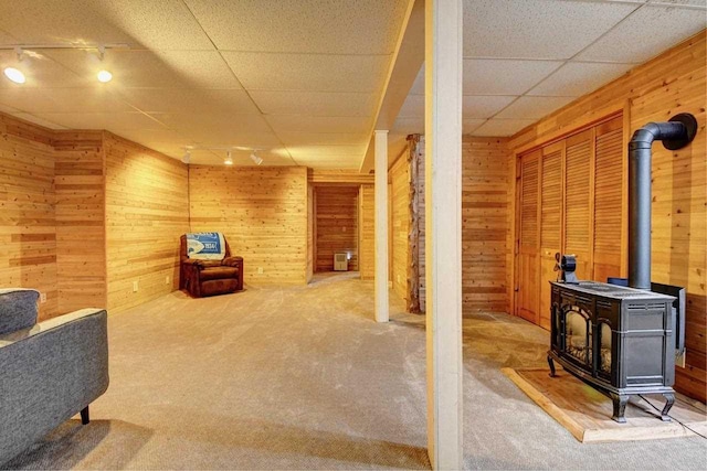 2382 Pleasant Valley Rd, Boyne City, MI 49712 - interior space with a wood stove, a paneled ceiling, wooden walls, and carpet floors