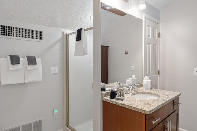 bathroom with a shower stall, vanity, visible vents, and a textured ceiling
