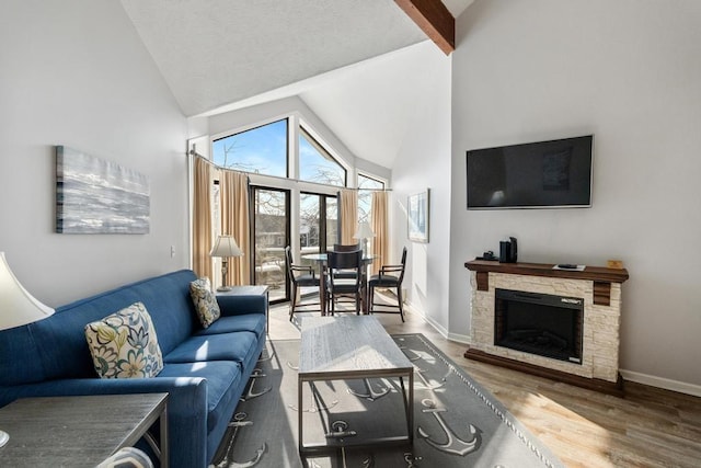 living room with baseboards, high vaulted ceiling, wood finished floors, and a fireplace