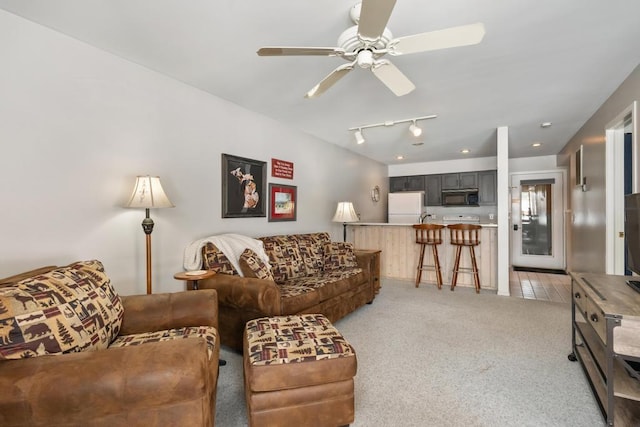living area with track lighting, a ceiling fan, and light colored carpet