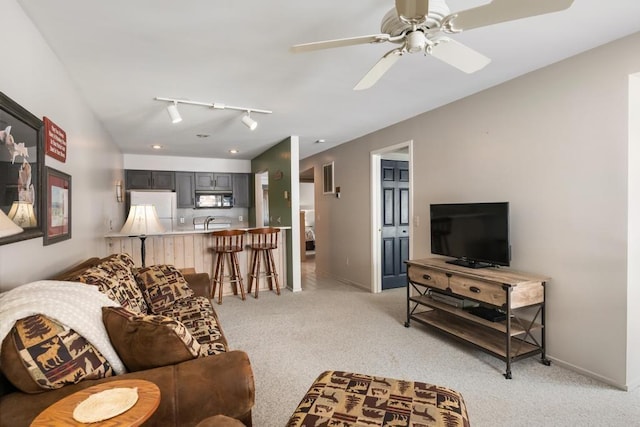 living area featuring track lighting, light colored carpet, baseboards, and a ceiling fan