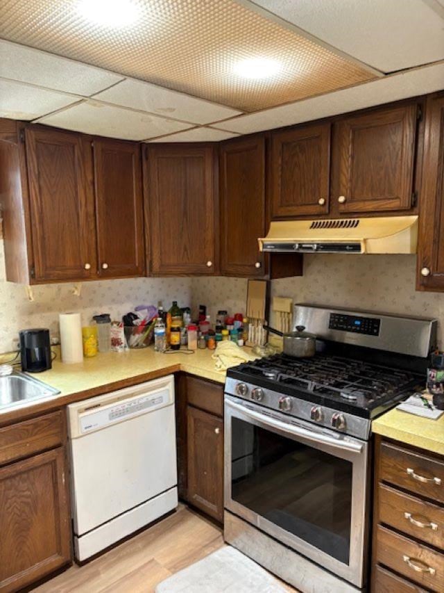 4462 E Brutus Rd, Alanson, MI 49706 - kitchen featuring light wood-type flooring, light countertops, under cabinet range hood, white dishwasher, and stainless steel range with gas cooktop