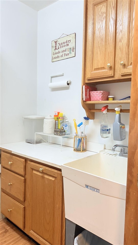 9196 NW Manley Rd, Alden, MI 49612 - clothes washing area with light wood finished floors and a sink