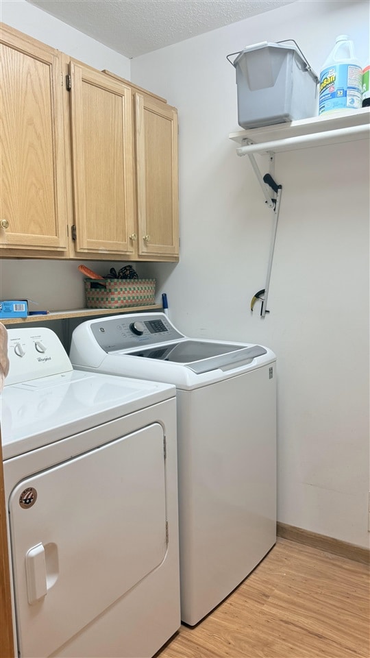 9196 NW Manley Rd, Alden, MI 49612 - laundry area with cabinet space, washing machine and clothes dryer, and light wood finished floors