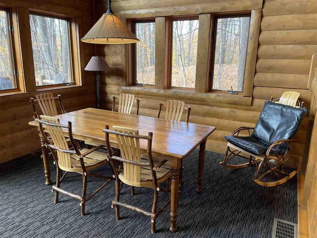 carpeted dining room featuring rustic walls and visible vents