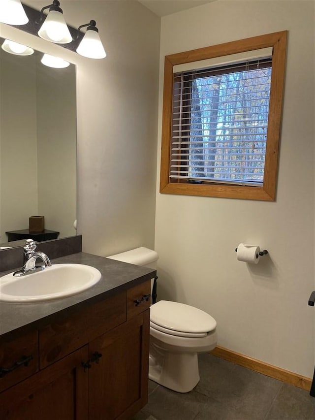 bathroom with baseboards, tile patterned flooring, vanity, and toilet