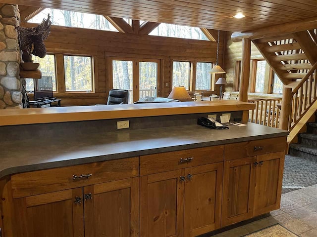 kitchen with wooden ceiling, brown cabinets, dark countertops, and plenty of natural light
