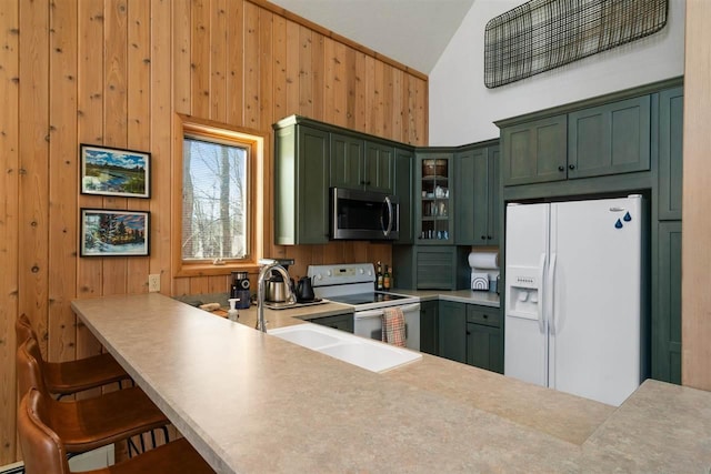 kitchen featuring wood walls, green cabinets, white appliances, and glass insert cabinets