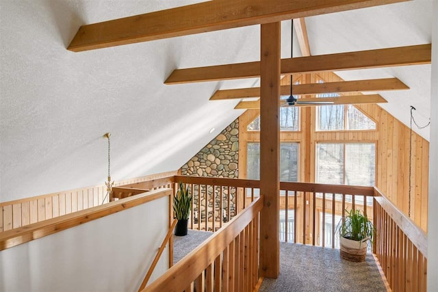 hallway featuring wooden walls, carpet flooring, and vaulted ceiling with beams