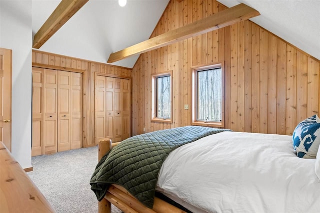 bedroom with vaulted ceiling with beams, wood walls, carpet, and multiple closets