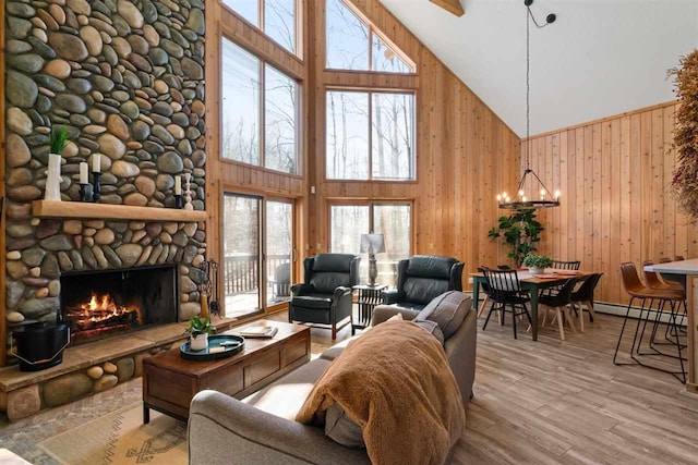 living area with wooden walls, wood finished floors, a healthy amount of sunlight, and high vaulted ceiling