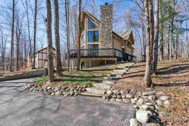 view of side of property featuring a chimney, stairs, stucco siding, and a deck