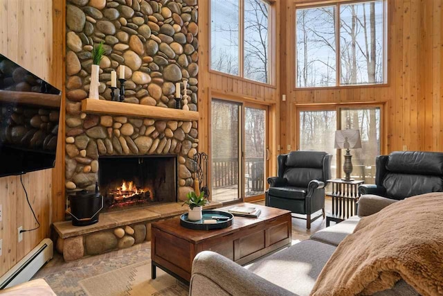 living room with a baseboard heating unit, wooden walls, a wealth of natural light, and a fireplace