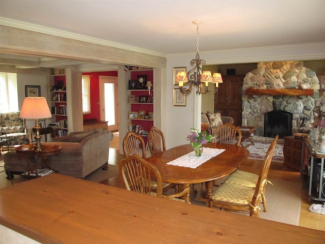 4251 Terpening Rd, Harbor Springs, MI 49740 - dining space with crown molding, a fireplace, a chandelier, and a healthy amount of sunlight