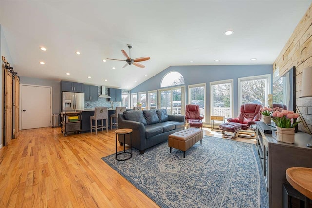 6001 N Silver Pines Dr, Bellaire, MI 49615 - living room with vaulted ceiling, a healthy amount of sunlight, a ceiling fan, and light wood-style flooring